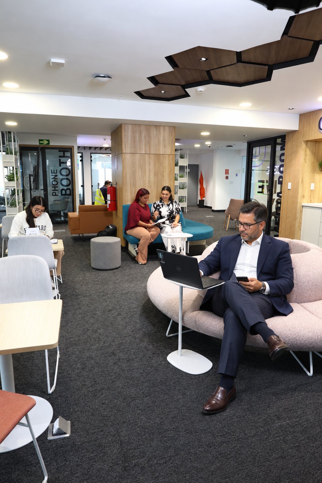 Ejecutivo trabajando con su laptop en el área abierta de Rworks Coworking, con phone booths y zonas de descanso en Torres de las Américas, Panamá